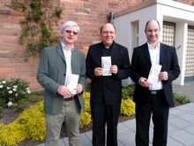 Das Foto zeigt (von links) Kantor Krystian Skoczowski mit Dechant Andreas Weber und Pfarrgemeinderatssprecher Ludwig Borowik vor dem „Geburtstagskind“ der St. Elisabethkirche mit dem Jubiläumsprogramm.